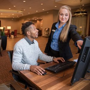person observing what another person is pointing at on a computer screen.