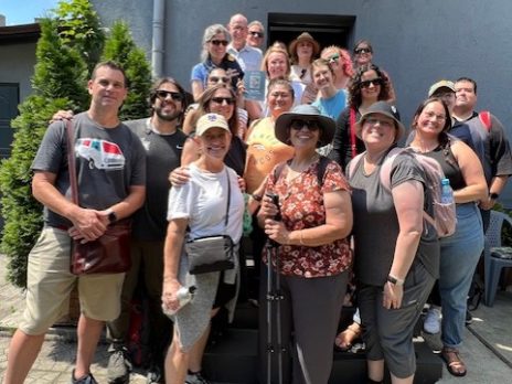 travel group in front of tree and building