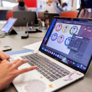 A graphic designer works on different logos on a laptop