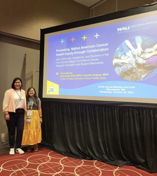 Carmenlita and Jennifer posing in front of presentation title slide at APHA