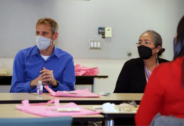 Dirk de Heer and Carol Goldtooth wearing masks and engaging in discussion