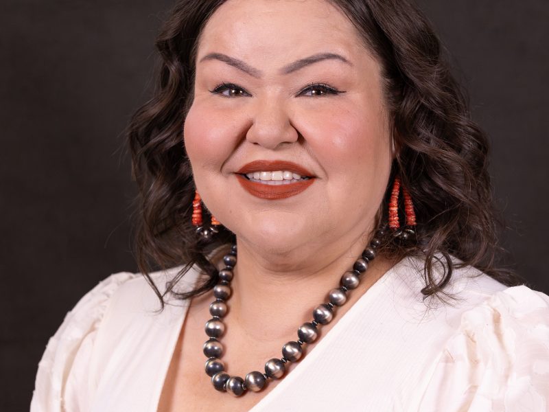 Diedre' Goodluck wearing a white top with a silver necklace and long coral earrings