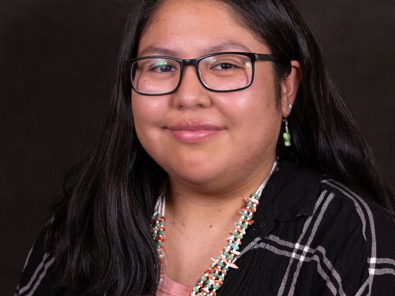 Utahana Dayzie wearing a black and white top with a green and coral beaded necklace and green butterfly earrings