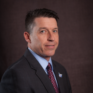 Brian Hummell wearing a suit with a red tie and blue button up