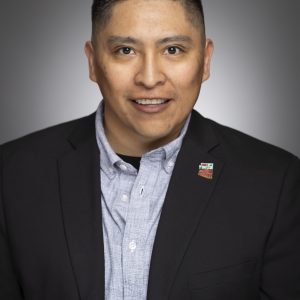 Kellen Polingyumptewa in a black suit with a light grey button up