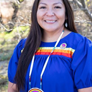 Tanya Lewis wearing a blue multicolored traditional top and large beaded necklace