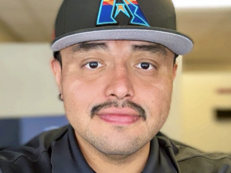 Billy Bragg wearing a dark gray polo and a black hat