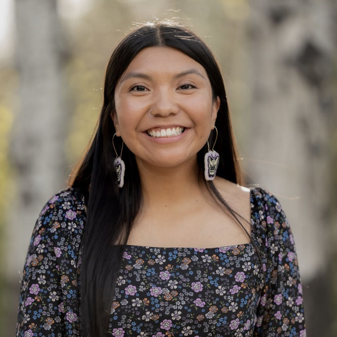 Jessica Sanchez wearing a black floral top with beaded butterfly earrings.