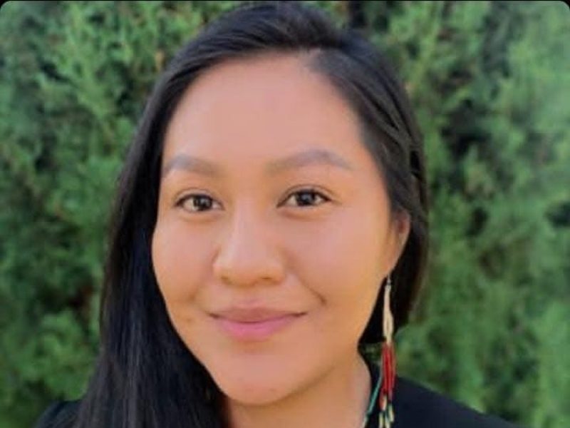 Trena Bizardi wearing a green top and black blazer with red and white earrings