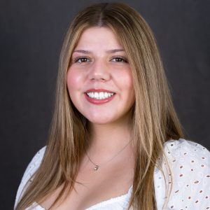 Headshot photo of Aiyana Chavez wearing a white top with a dark gray background.