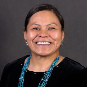 Headshot photo of Tasha Nez wearing a black top and turquoise necklace and earrings.