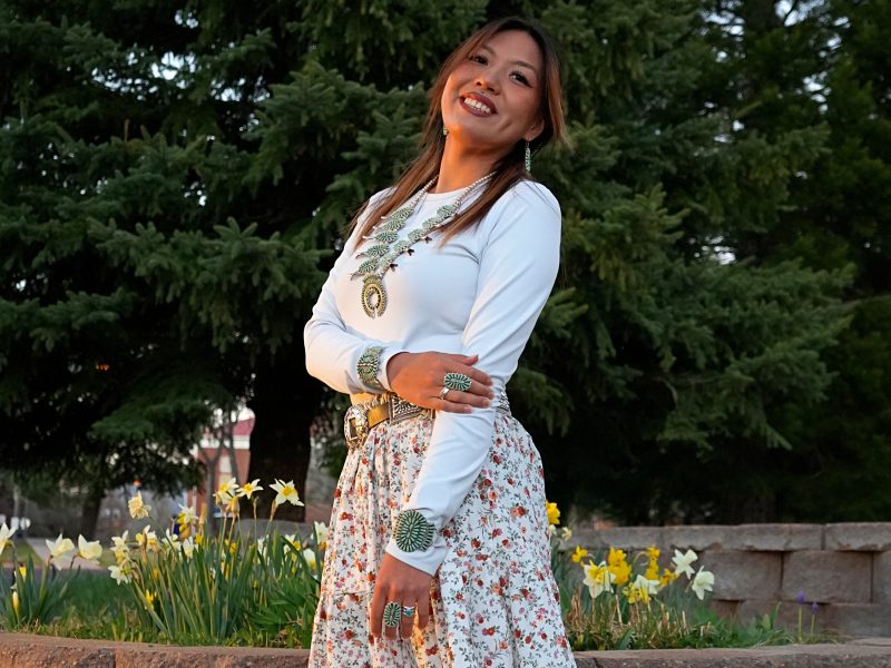 Headshot photo of Cynthia Nelson wearing a white top with a floral skirt and wrap up moccasins adorned by turquoise jewelry