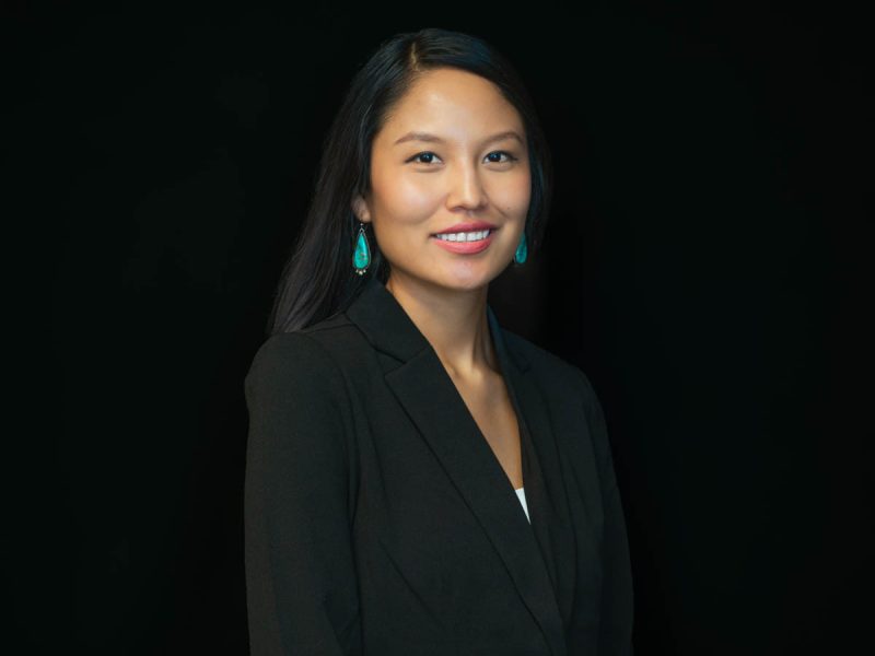 Headshot photo of Melaina Shirley wearing a black blazer with turquoise earrings