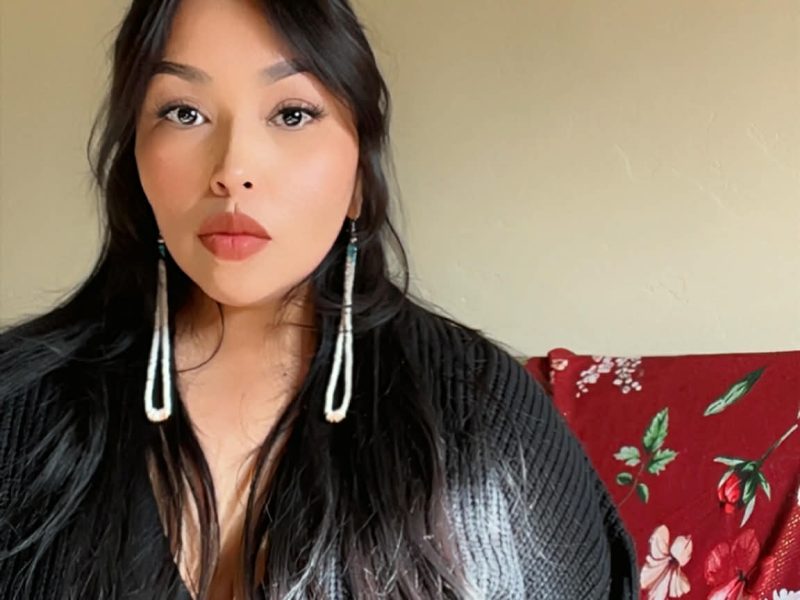 Headshot photo of Tianna Curley wearing a black cardigan and long beaded earrings