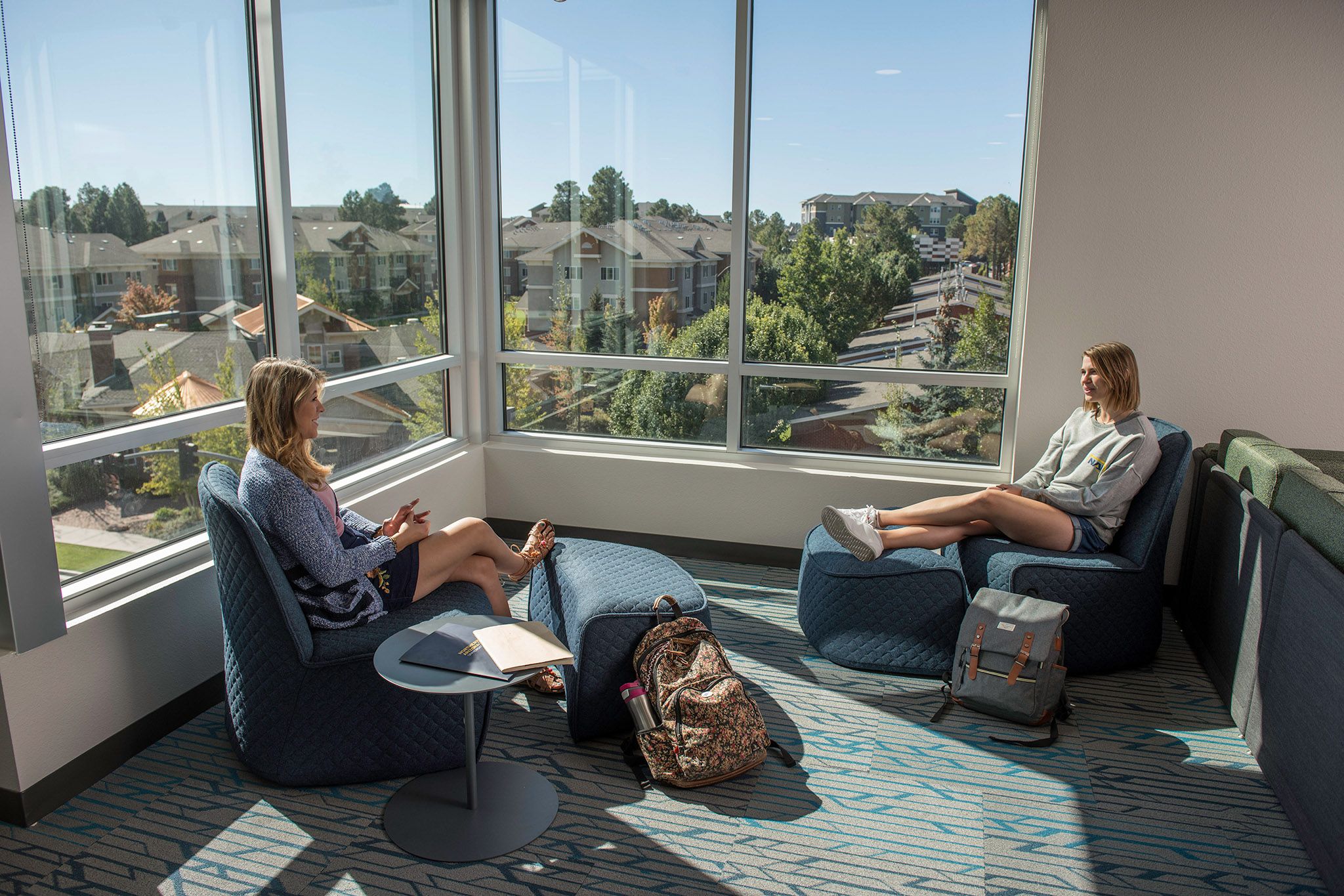 Two students sitting on chairs chatting in the Honors Dorm.