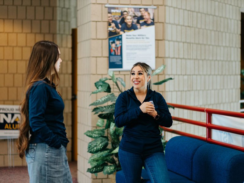 Communication specialist talking to a student in a hallway.