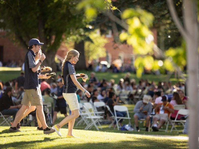 NAU staff walking while holding food at new student orientation event.