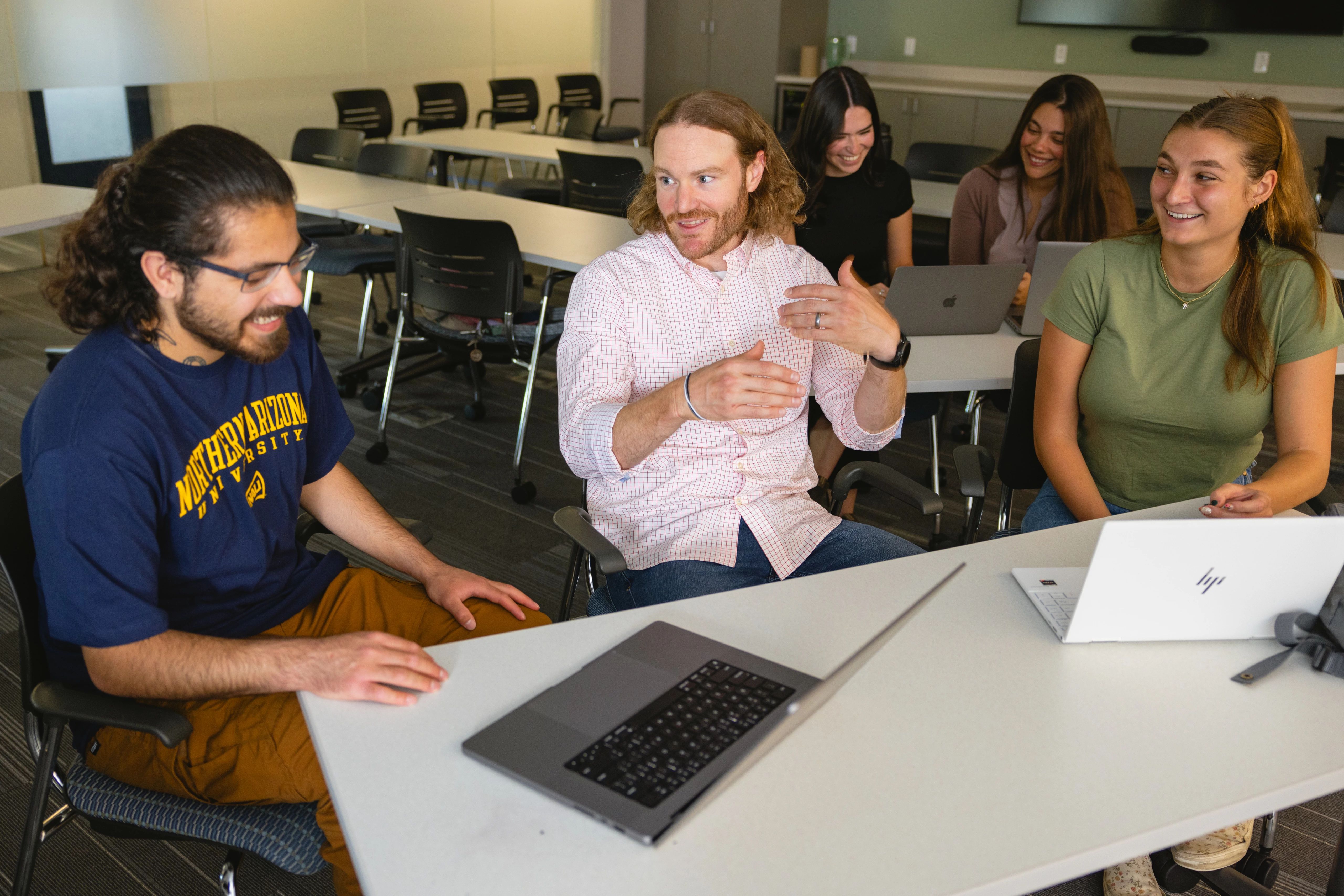 Graduate students talking to graduate school professor in classroom.