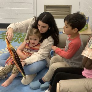 studentworkerreadingbooktotwochildren