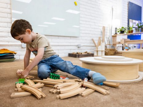 child playing on the ground with train tracks