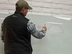 A child's dad draws a picture of a burrow on a dry erase board, next to a picture of a mouse in a burrow on the television.