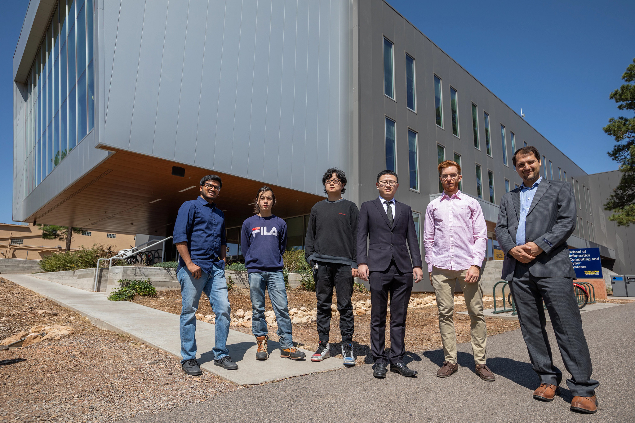 Students and teacher stand outside of building.