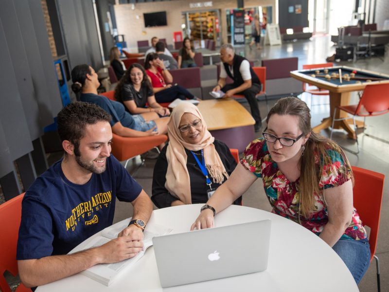 three people sitting in front of a laptop computer
