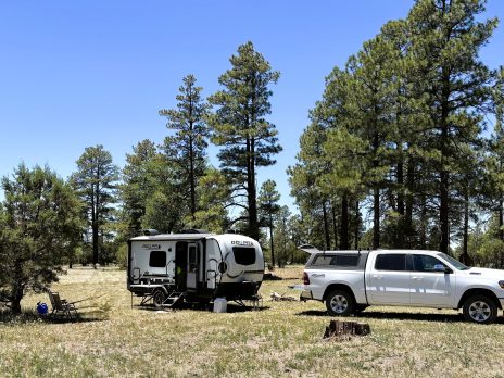 A parked truck with a camper attached to it in a camping area of the NAU Hat Ranch.
