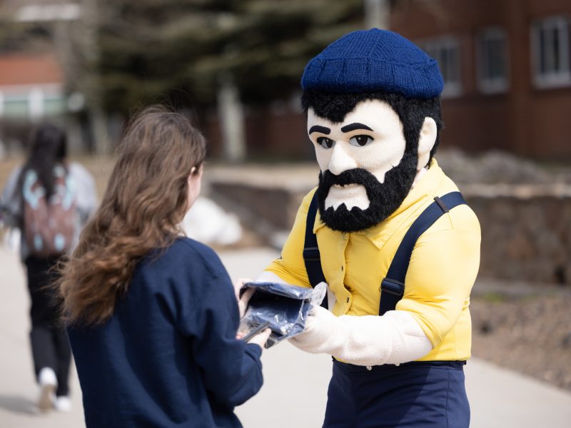 N A U Louie handing student swag out on Giving Day.