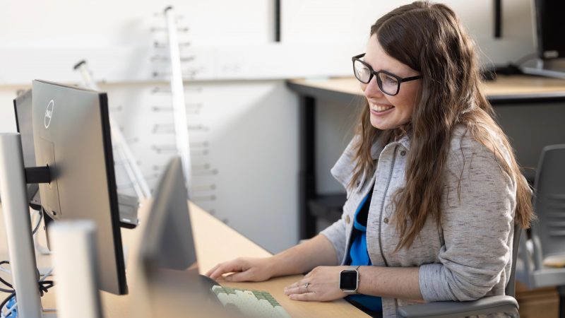 Vigil Hayes sitting and smiling in front of a computer.