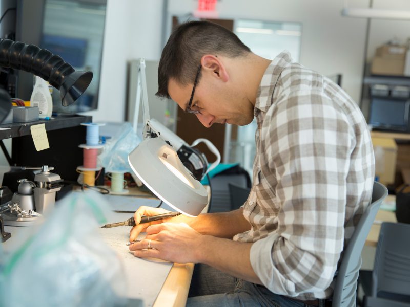 Student working on soldering an object.