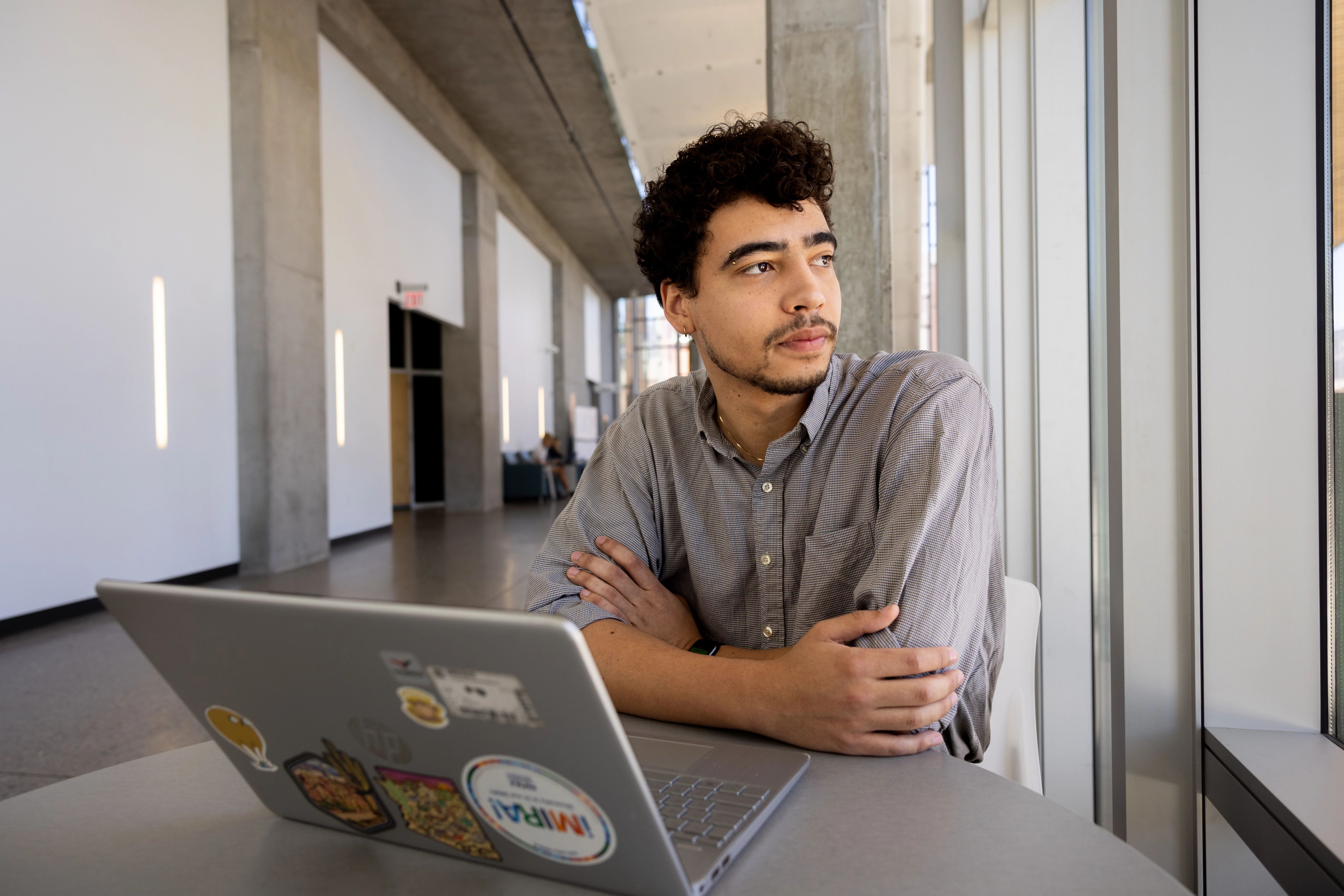 Student sitting in the Science and Health building on a laptop.