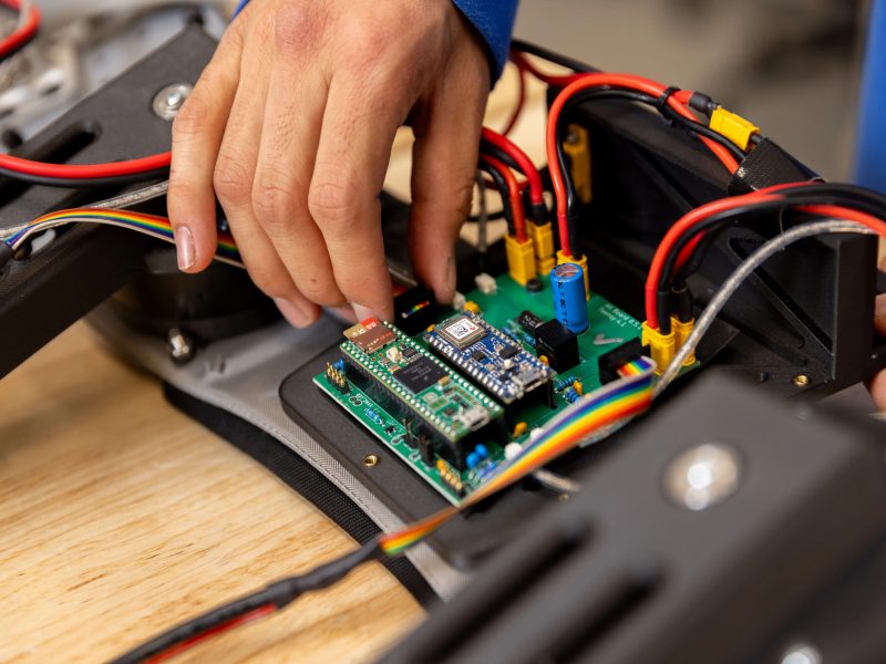 A pair of hands working on a circuit board for a piece of equipment.