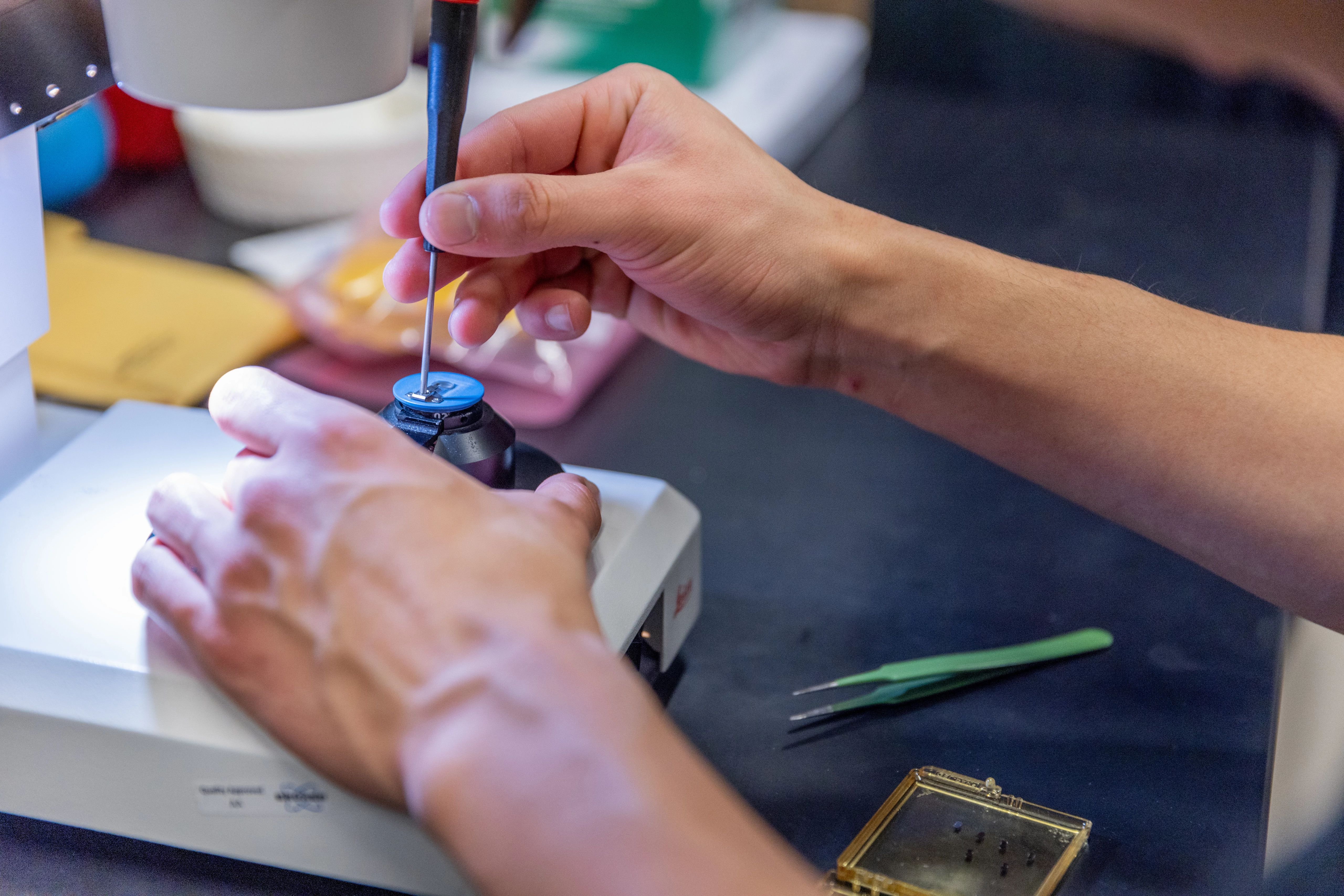 A pair of hands performing nano imaging under a microscope.