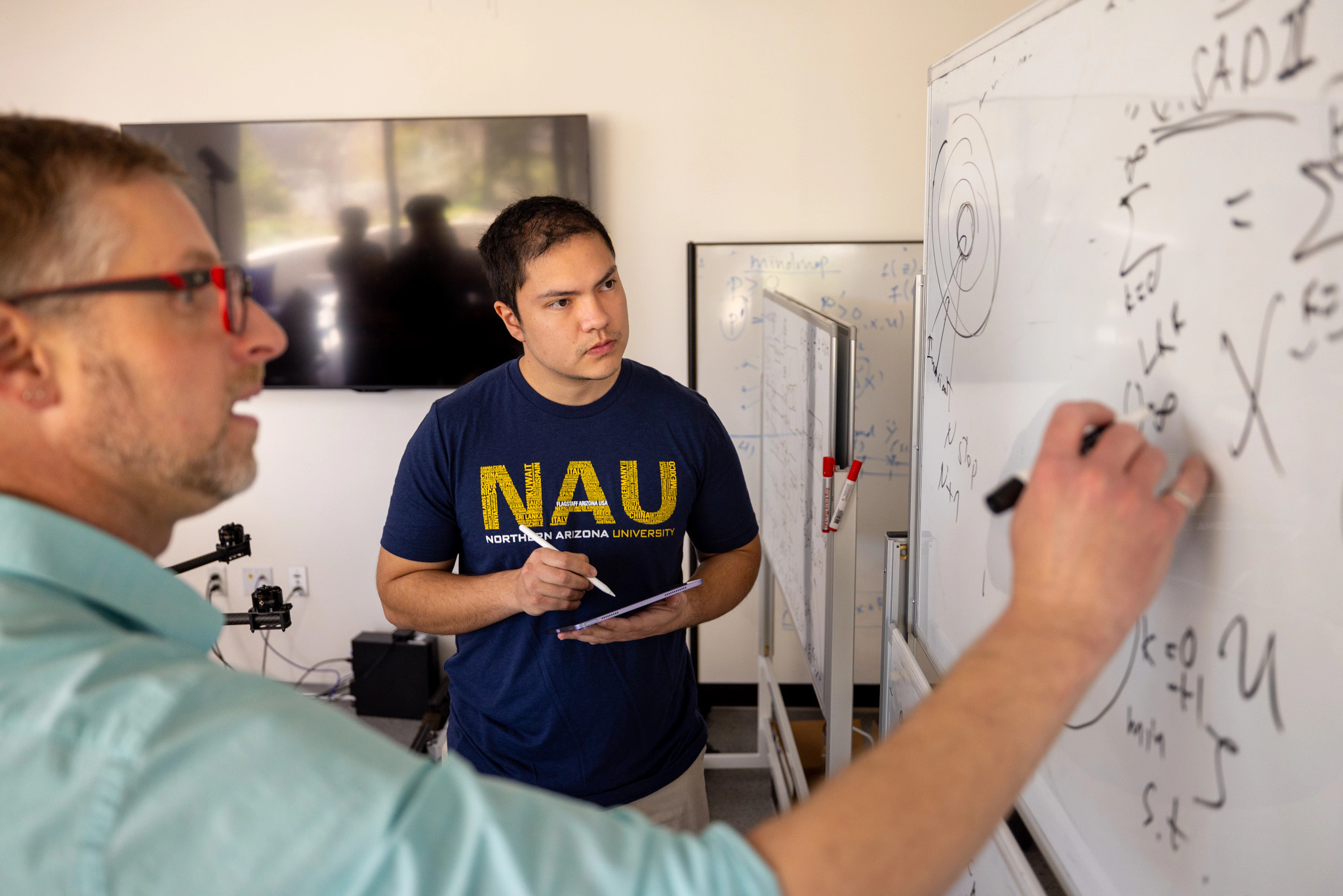 Professor working with student through a problem on a whiteboard.