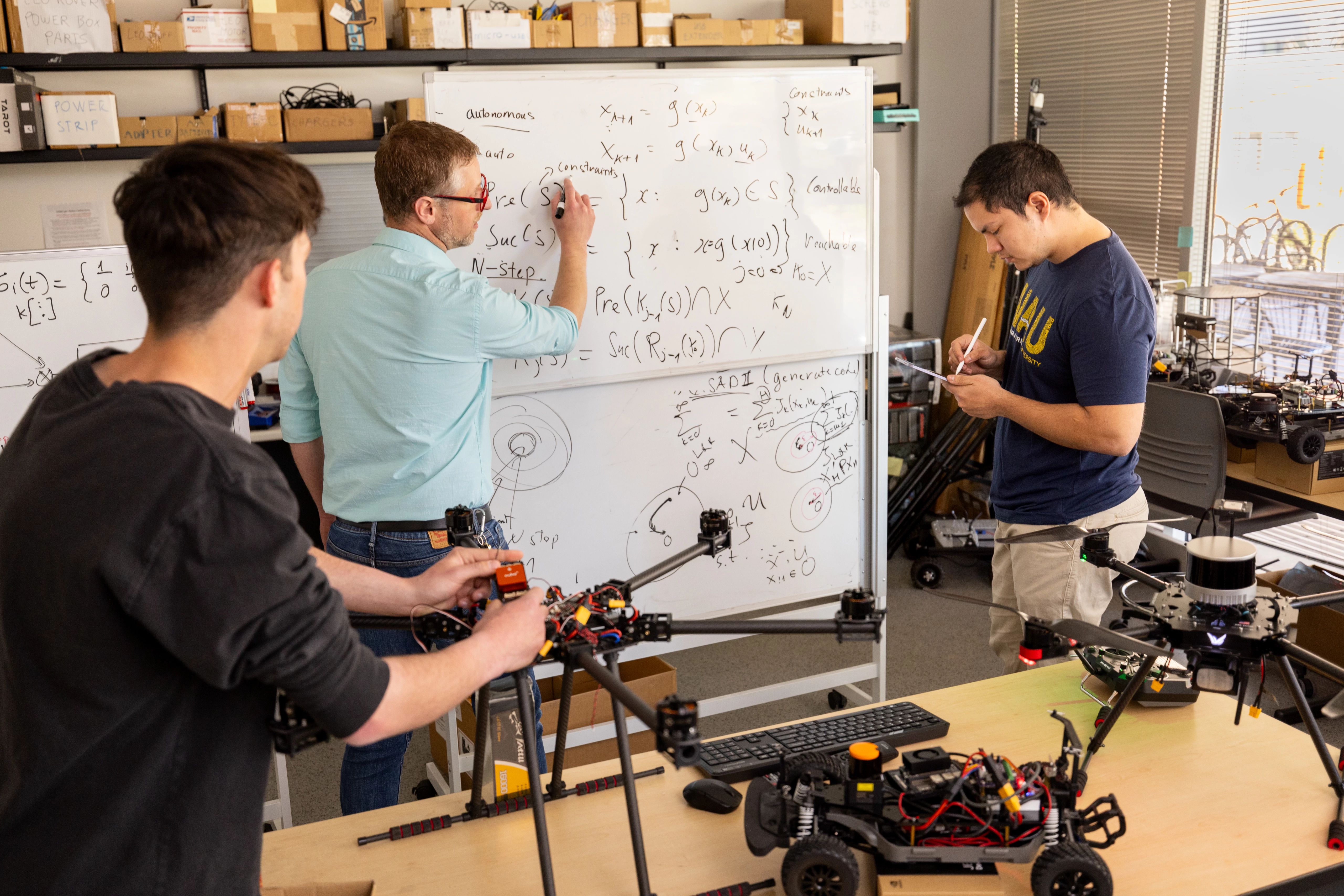 Students and their professor performing calculations on a whiteboard.