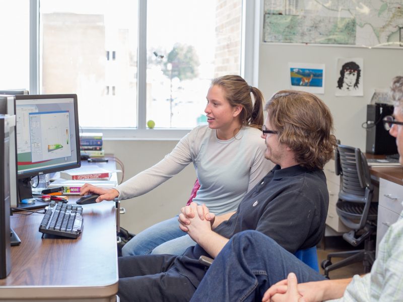 Student showing professors her work on the computer.