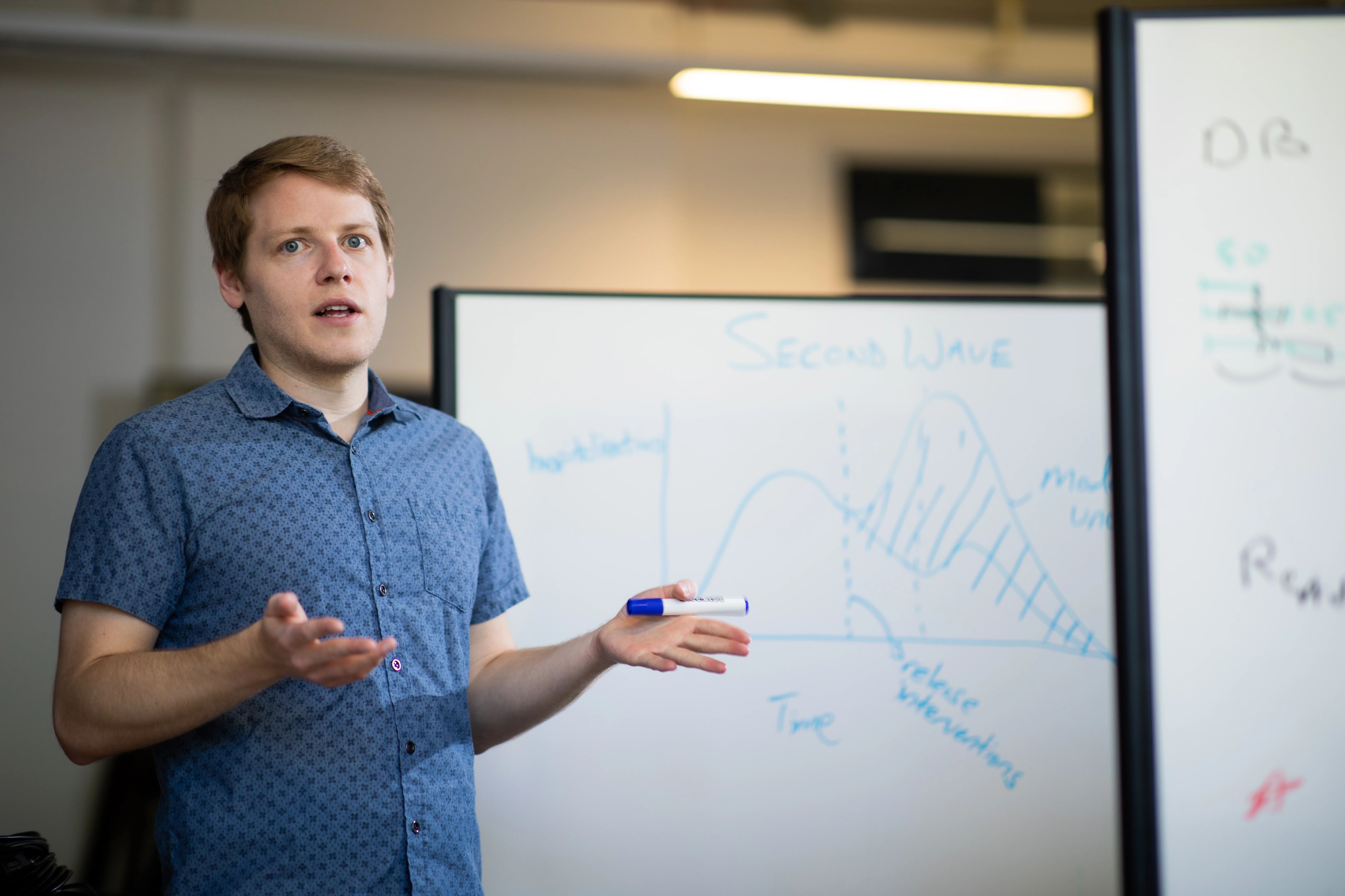 Mihaljevic explaining his research on a whiteboard.