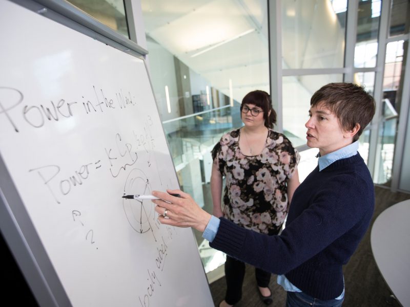 Professor and student working together at whiteboard.