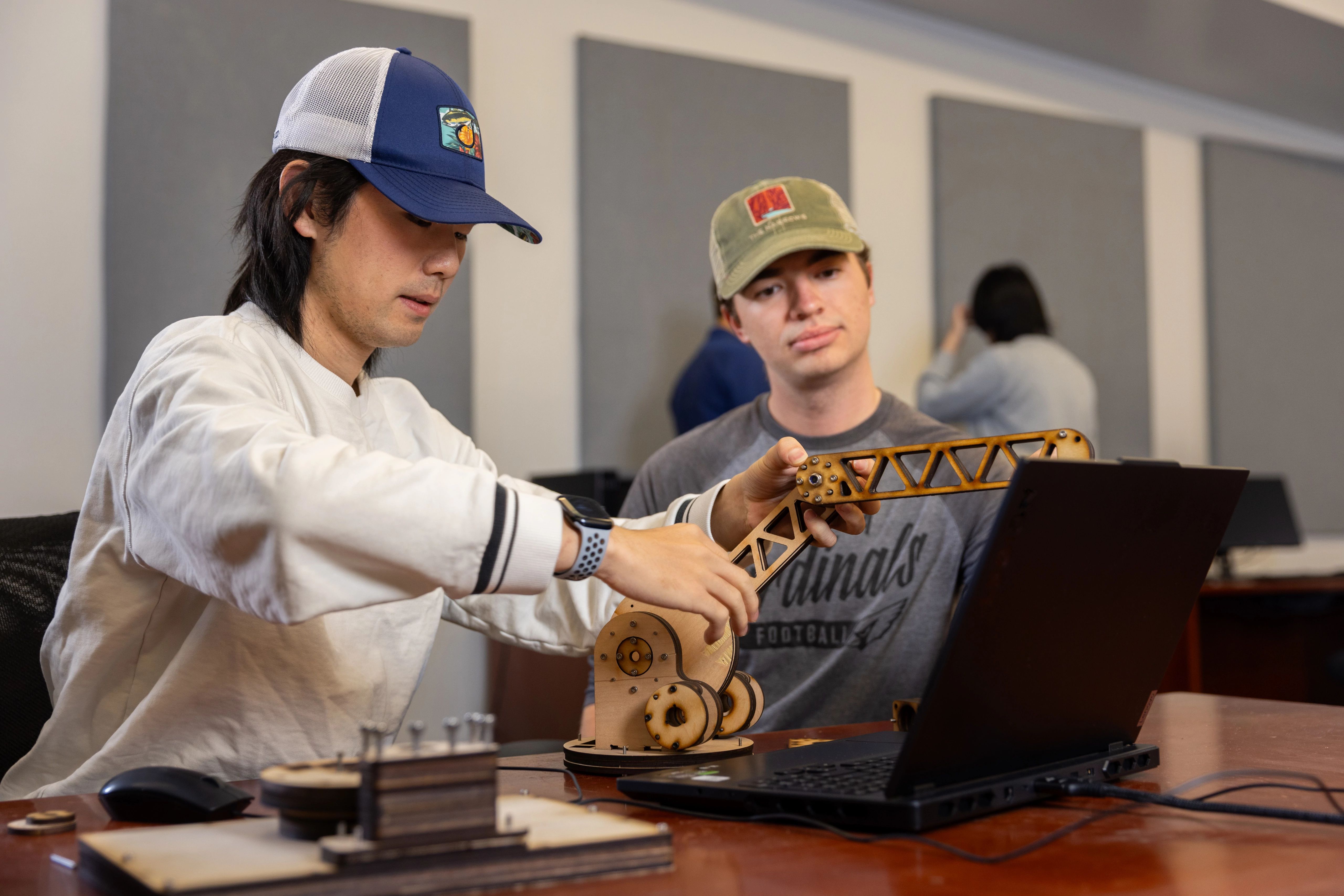 Two students working together to build a small crane mechanism.