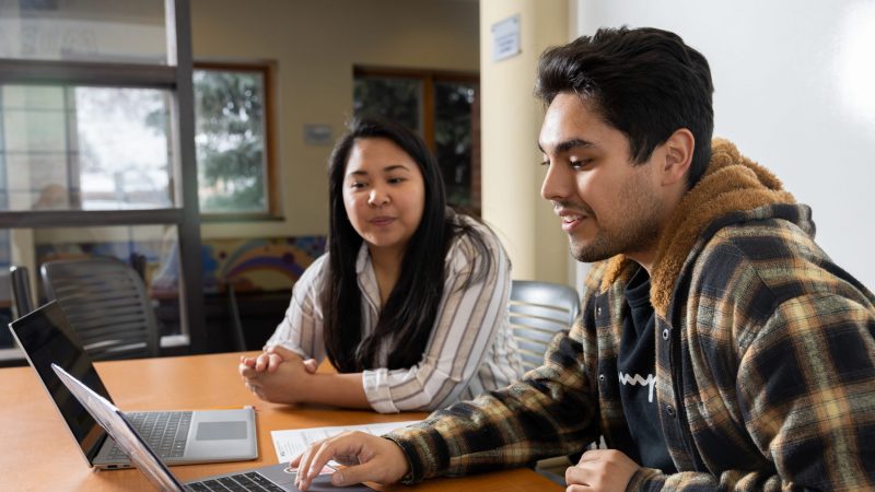 Advisor sitting at table with N A U student.