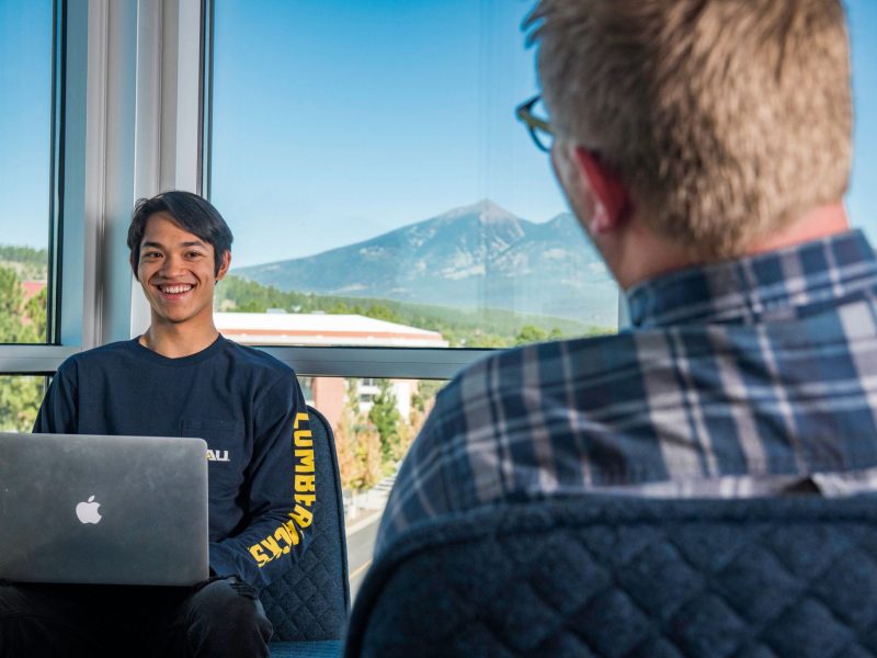 Student sitting with laptop in front of advisor.