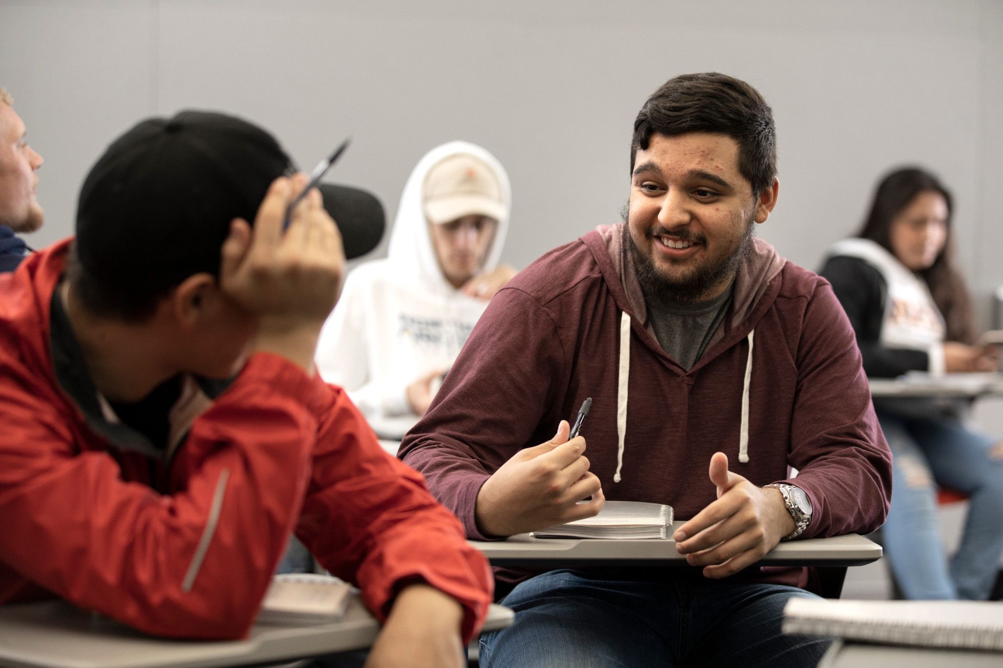 One student talking with other student in classroom.