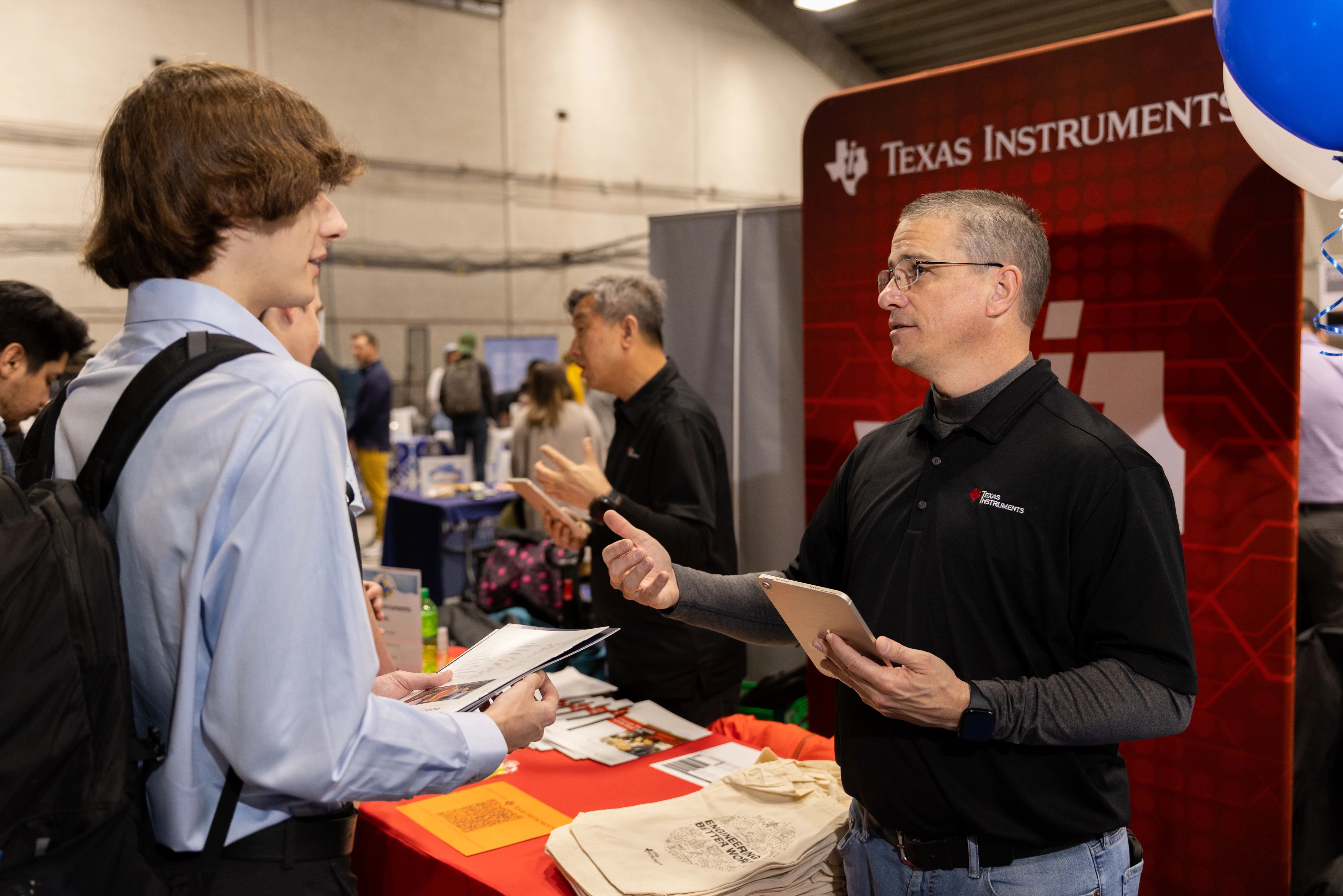 Student talking with Texas Instruments representative.