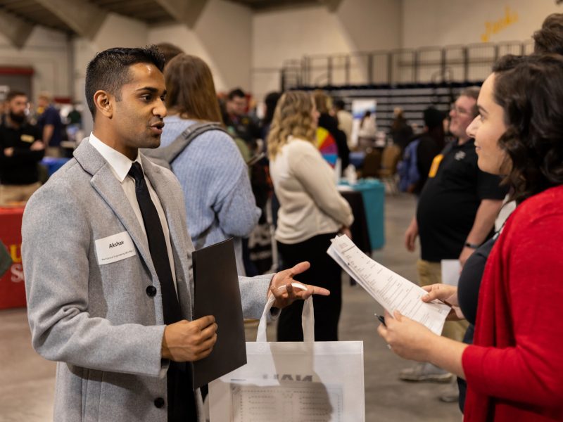 Man talking to woman at N A U career fair.