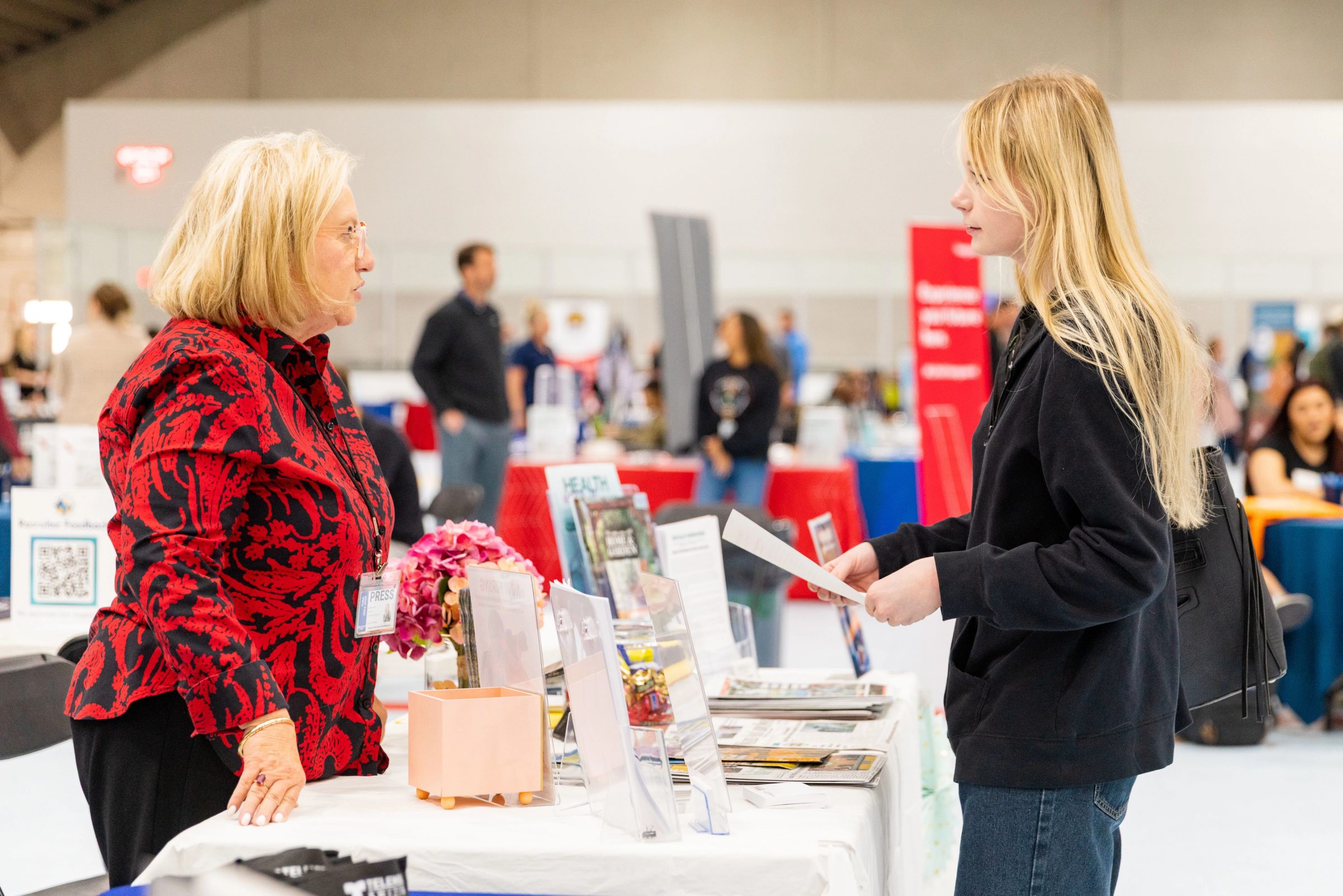 Student speaking with professional at a table and holding her resume