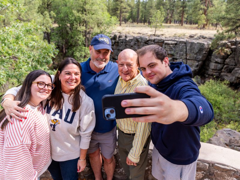 A family smiles while taking a selfie together in Flagstaff.