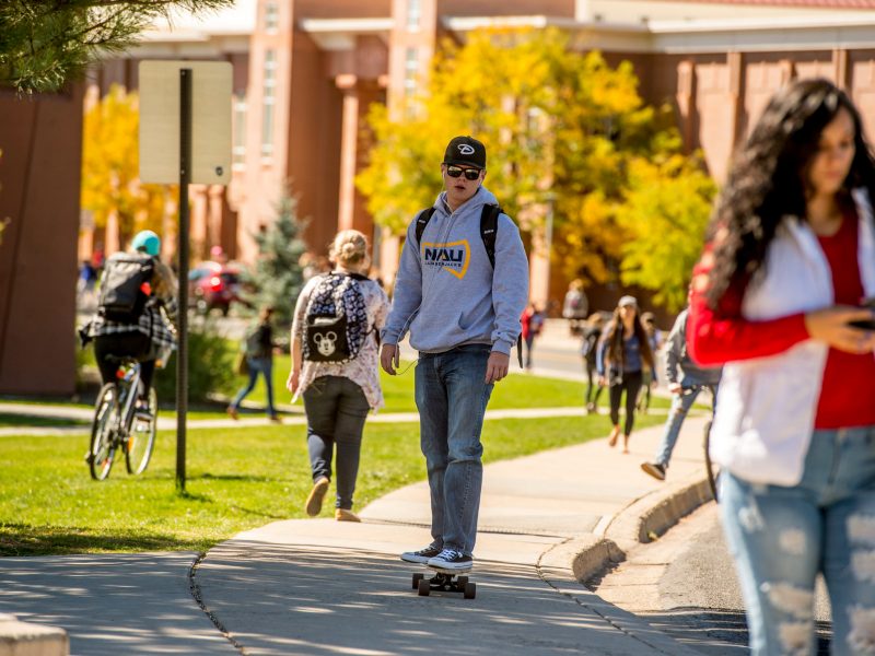 NAU student rides a skateboard on Flagstaff campus.