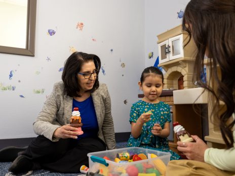 Woman plays with young child in SLP clinic.
