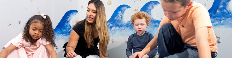 SLP therapist plays with three children in the clinic.